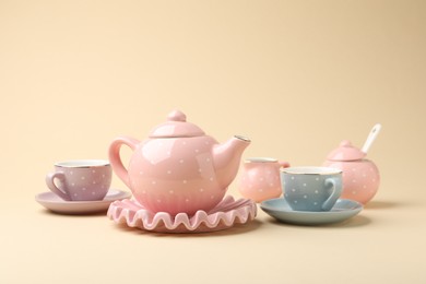 Photo of Beautiful ceramic tea set for children on beige background