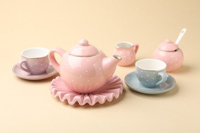 Photo of Beautiful ceramic tea set for children on beige background, closeup