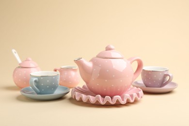 Photo of Beautiful ceramic tea set for children on beige background, closeup
