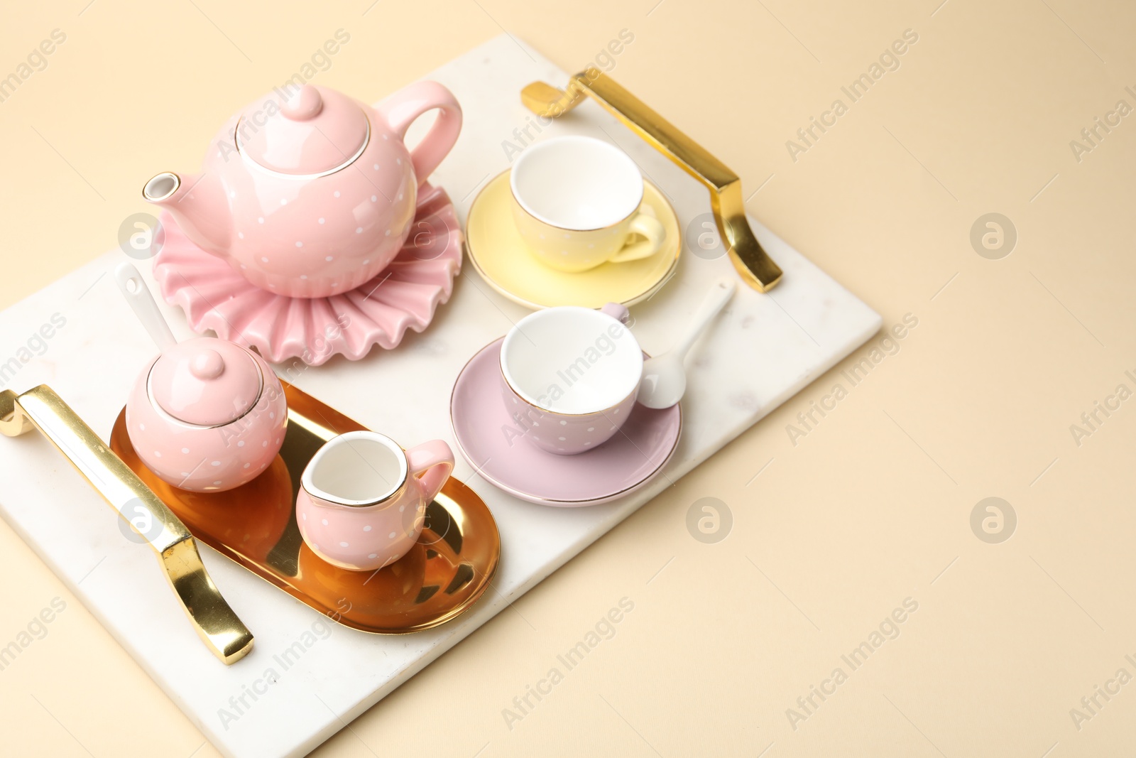 Photo of Tray with beautiful ceramic tea set for children on beige background. Space for text