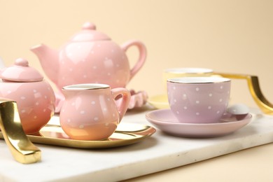 Photo of Tray with beautiful ceramic tea set for children on beige background, closeup