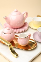 Photo of Tray with beautiful ceramic tea set for children on beige background, closeup