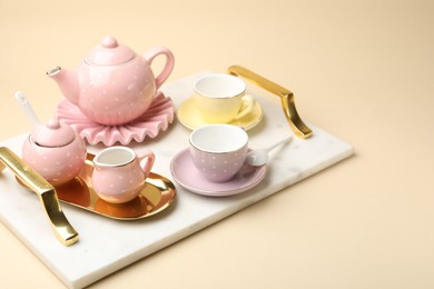 Photo of Tray with beautiful ceramic tea set for children on beige background, closeup. Space for text
