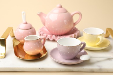 Photo of Tray with beautiful ceramic tea set for children on beige background, closeup
