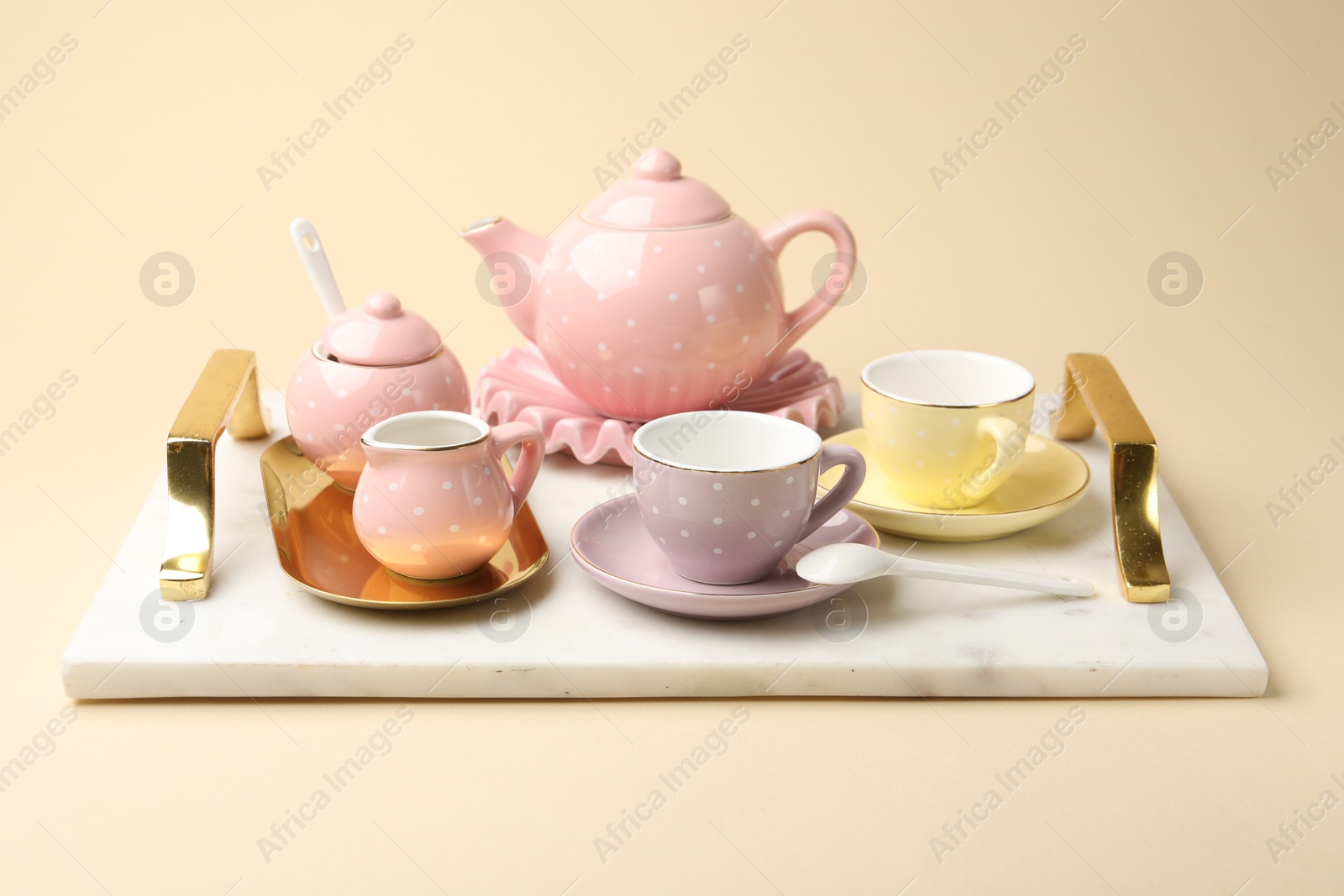 Photo of Tray with beautiful ceramic tea set for children on beige background