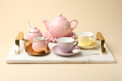 Photo of Tray with beautiful ceramic tea set for children on beige background