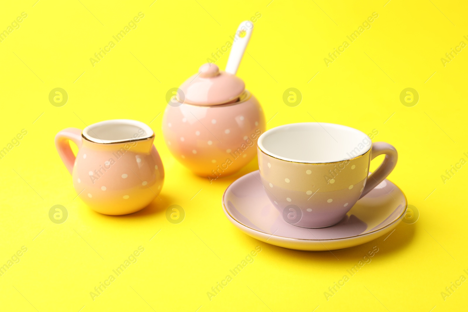 Beautiful ceramic tea set for children on yellow background, closeup Photo of Beautiful ceramic tea set for children on yellow background, closeup