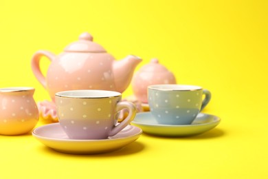 Photo of Beautiful ceramic tea set for children on yellow background, closeup