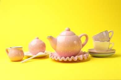 Photo of Beautiful ceramic tea set for children on yellow background