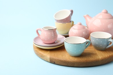 Photo of Beautiful ceramic tea set for children on light blue background, closeup. Space for text