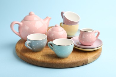 Photo of Beautiful ceramic tea set for children on light blue background, closeup