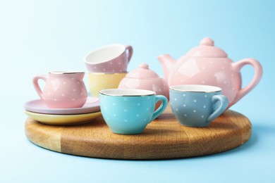 Photo of Beautiful ceramic tea set for children on light blue background, closeup