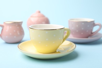 Photo of Beautiful ceramic tea set for children on light blue background, closeup