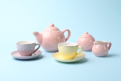Photo of Beautiful ceramic tea set for children on light blue background