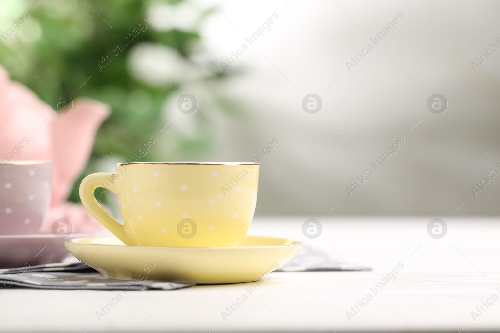 Ceramic tea set for children. Beautiful cups on white wooden table against blurred background, closeup with space for text Photo of Ceramic tea set for children. Beautiful cups on white wooden table against blurred background, closeup with space for text