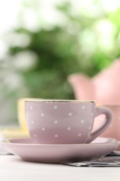 Photo of Ceramic tea set for children. Beautiful cup on white wooden table against blurred background, closeup with space for text