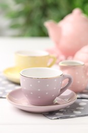 Photo of Beautiful ceramic tea set for children on white wooden table against blurred background, closeup
