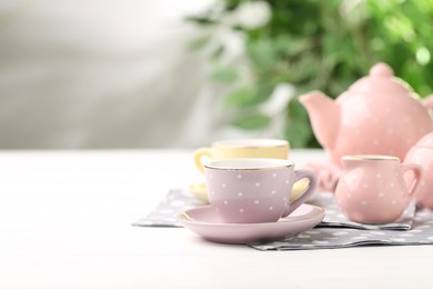 Photo of Beautiful ceramic tea set for children on white wooden table against blurred background, closeup. Space for text