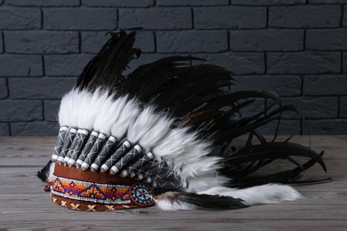 Photo of Native American chief headdress (feathered war bonnet) on wooden surface against gray brick wall