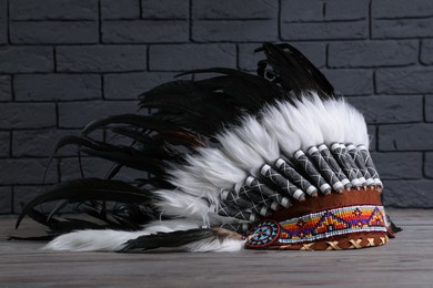 Photo of Native American chief headdress (feathered war bonnet) on wooden surface against gray brick wall