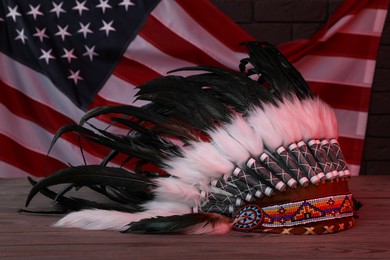 Photo of Native American chief headdress (feathered war bonnet) on wooden surface against American flag in red light