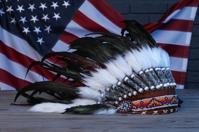 Photo of Native American chief headdress (feathered war bonnet) on wooden surface against American flag