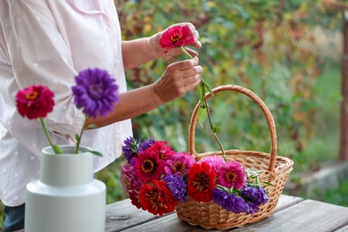 Photo of Senior woman making beautiful bouquet of flowers at wooden table in garden, closeup