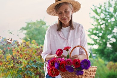 Photo of Senior woman making beautiful bouquet of flowers in garden