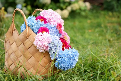 Photo of Beautiful bouquet of flowers in bag on green grass outdoors, closeup. Space for text