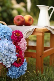 Photo of Beautiful bouquet of flowers, apples and jug in garden, closeup