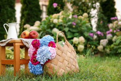Photo of Beautiful bouquet of flowers, apples and jug in garden, space for text