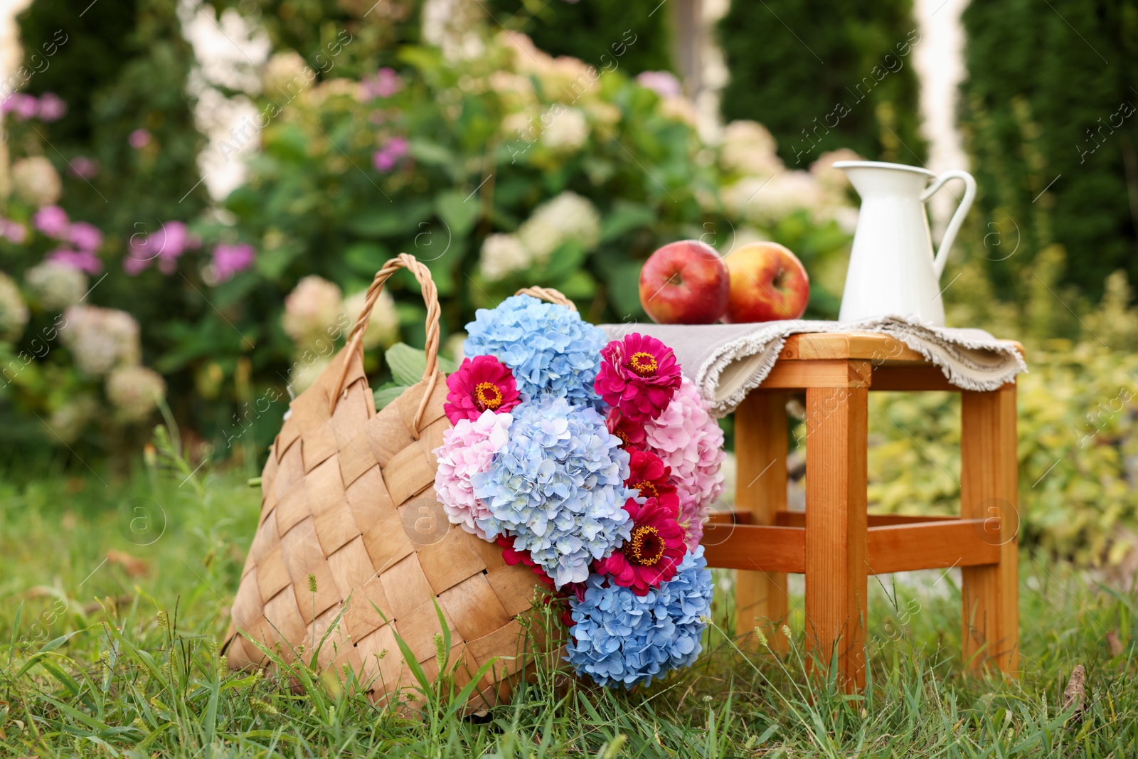 Photo of Beautiful bouquet of flowers, apples and jug in garden