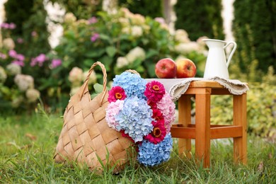 Photo of Beautiful bouquet of flowers, apples and jug in garden
