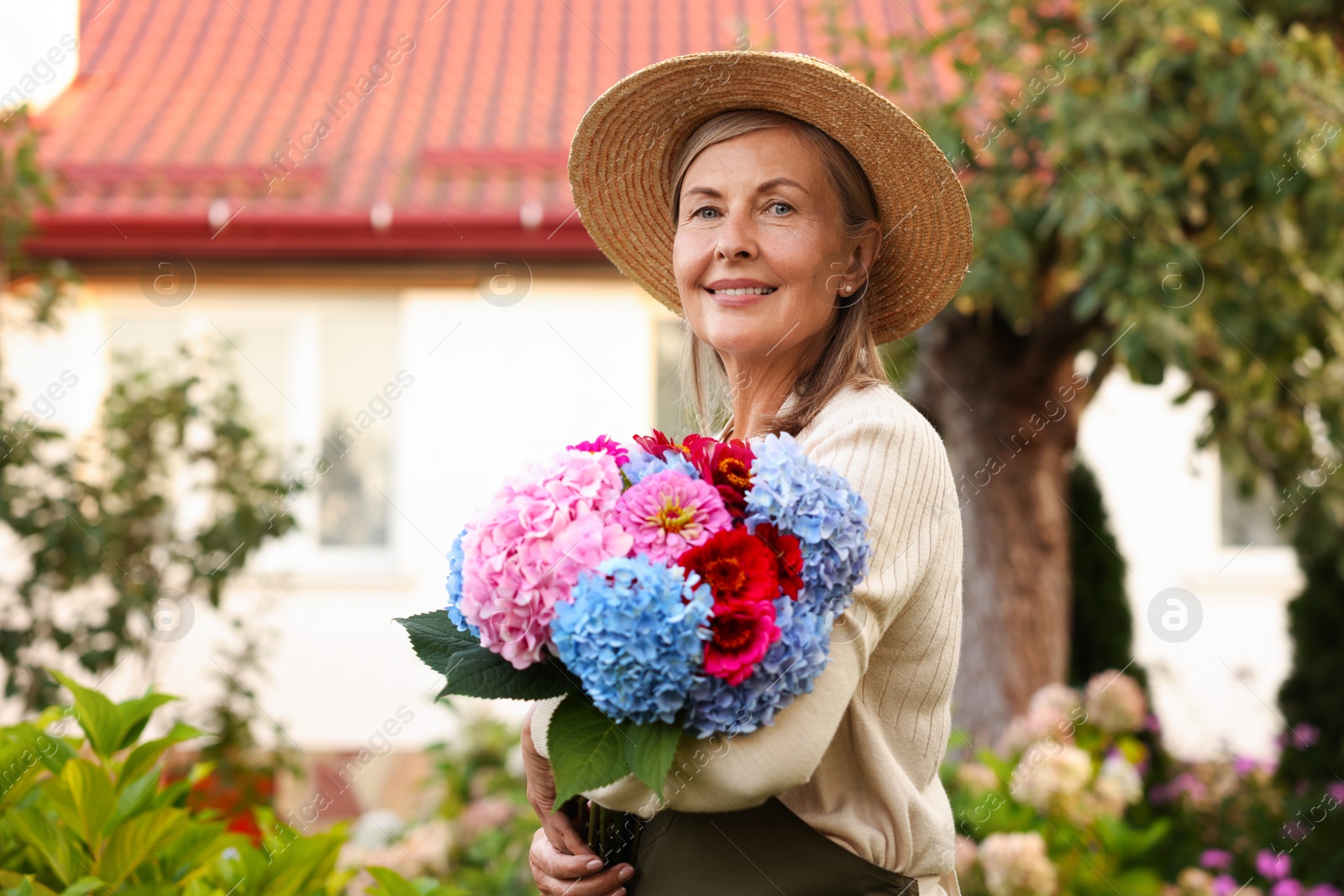 Senior woman with beautiful bouquet of flowers in garden Photo of Senior woman with beautiful bouquet of flowers in garden