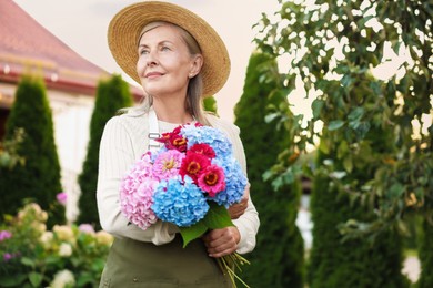 Photo of Senior woman with beautiful bouquet of flowers in garden, space for text