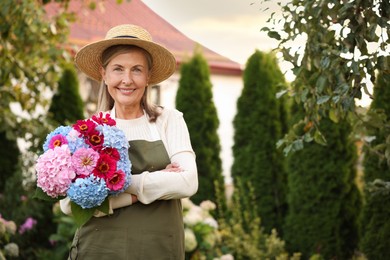 Photo of Senior woman with beautiful bouquet of flowers in garden, space for text
