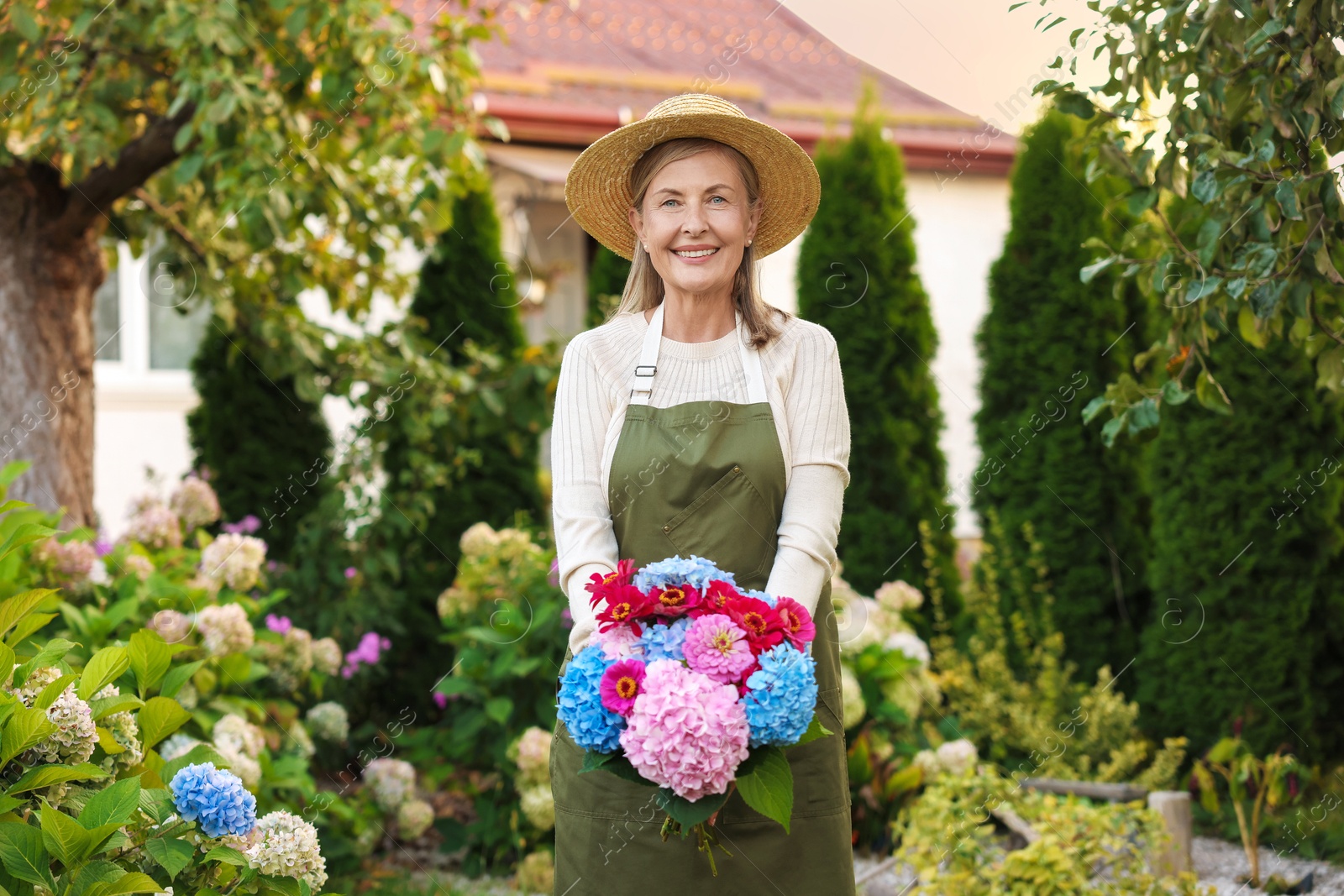 Senior woman with beautiful bouquet of flowers in garden Photo of Senior woman with beautiful bouquet of flowers in garden
