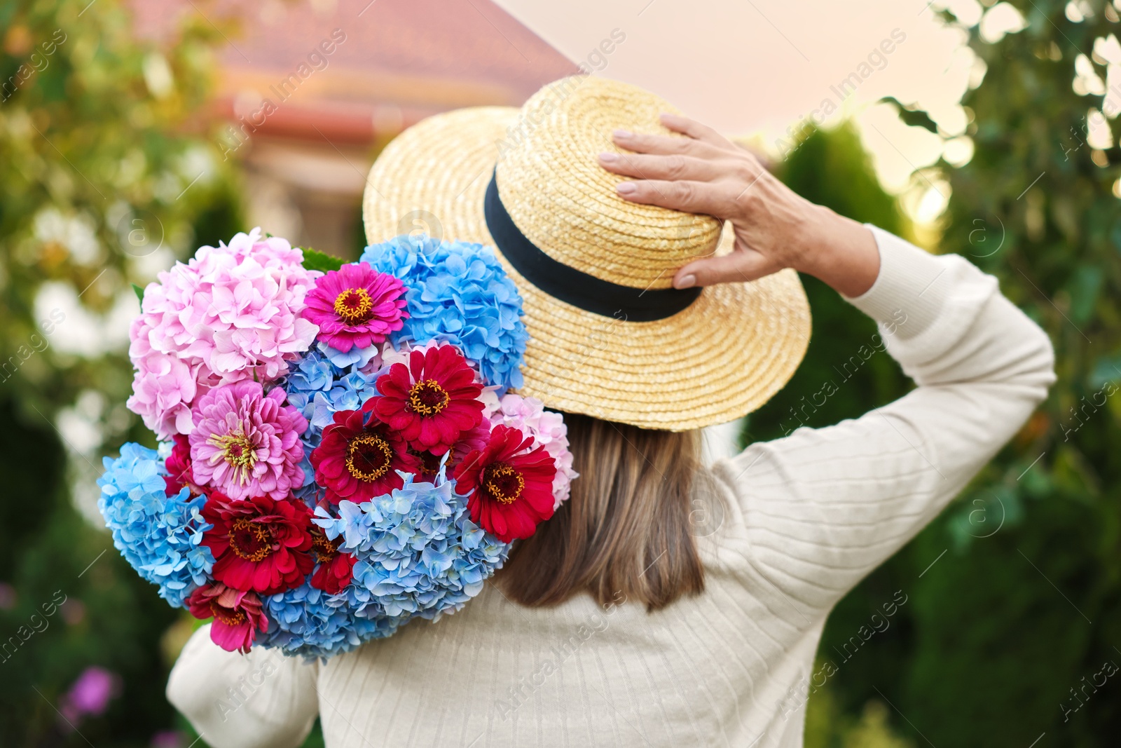 Senior woman with beautiful bouquet of flowers in garden, back view Photo of Senior woman with beautiful bouquet of flowers in garden, back view