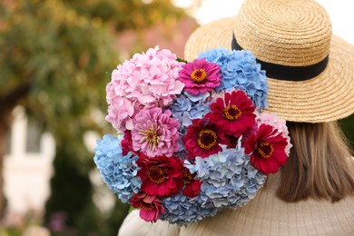 Photo of Senior woman with beautiful bouquet of flowers in garden, back view. Space for text