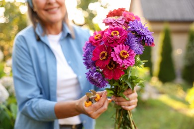 Photo of Senior woman with bouquet of flowers and pruner in garden, closeup