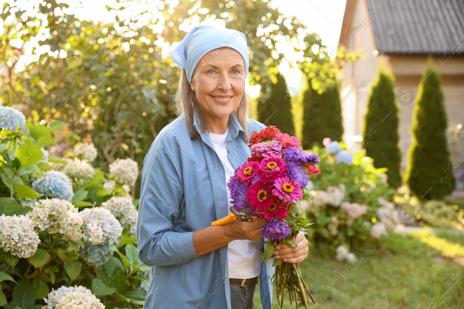 Senior woman with bouquet of flowers and pruner in garden Photo of Senior woman with bouquet of flowers and pruner in garden