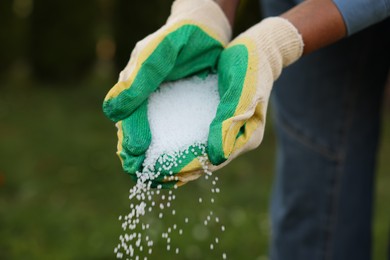 Photo of Woman pouring fertilizer outdoors, closeup. Gardening time