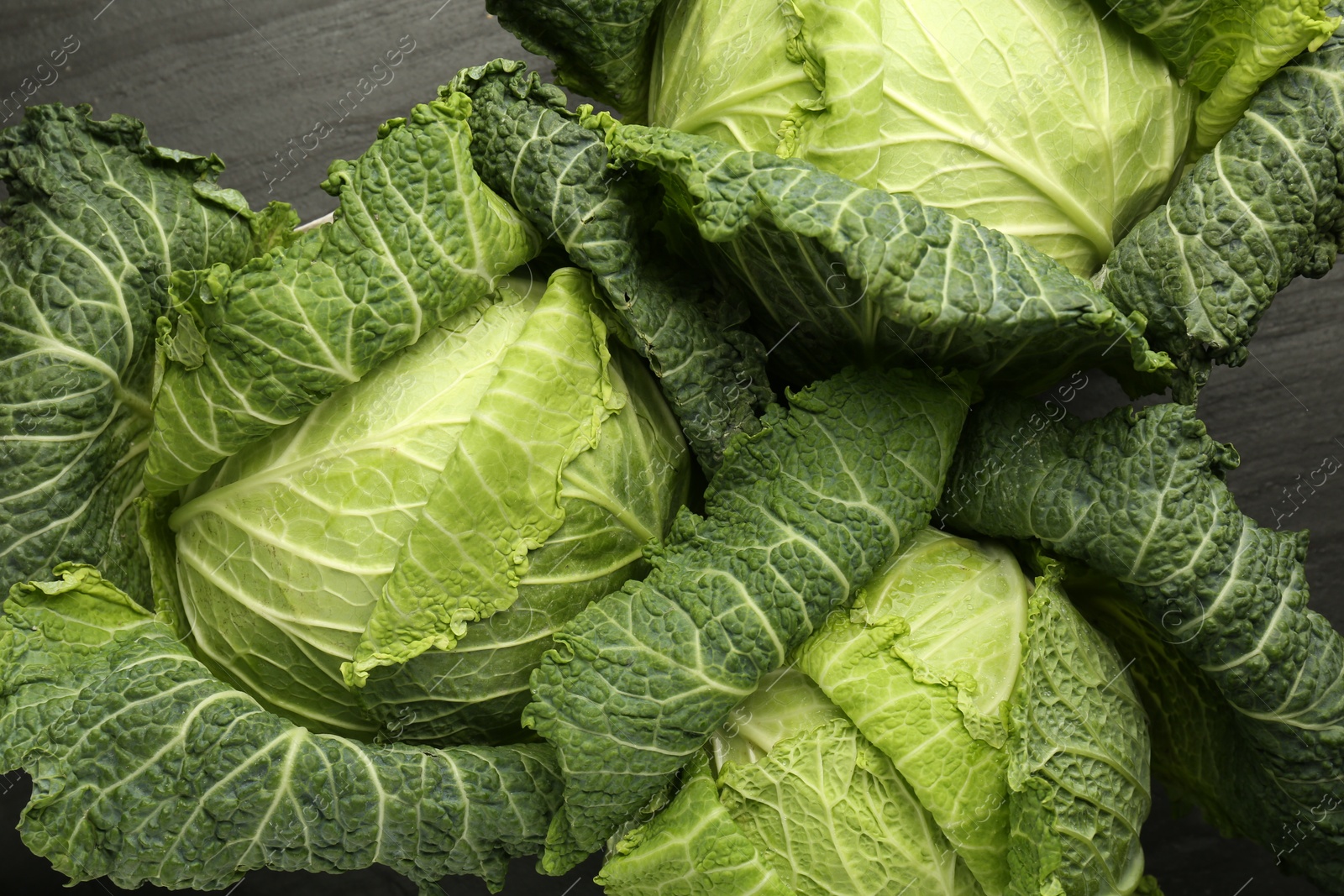 Photo of Fresh Savoy cabbages on black textured table, flat lay