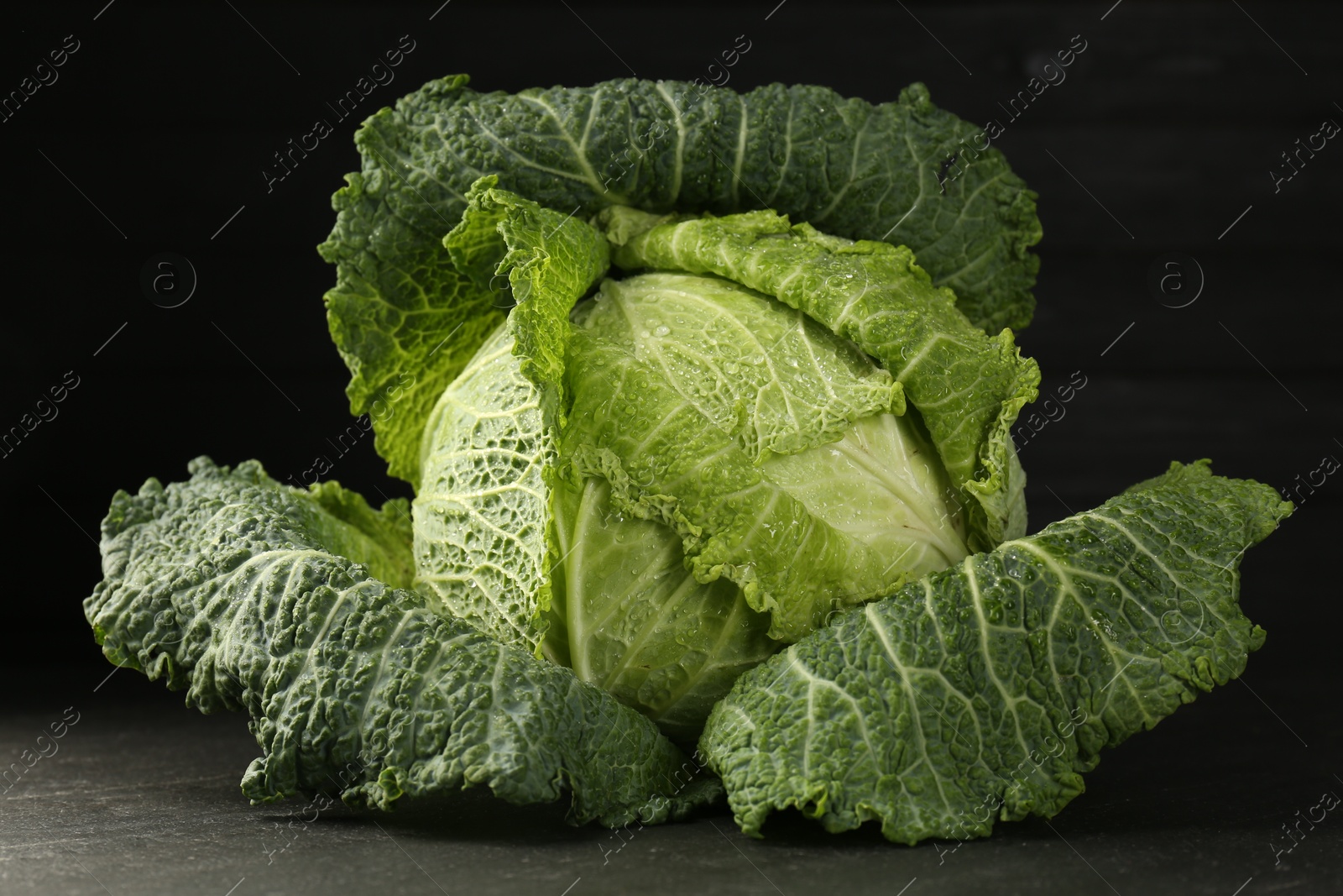 Photo of Fresh Savoy cabbage on dark table, closeup