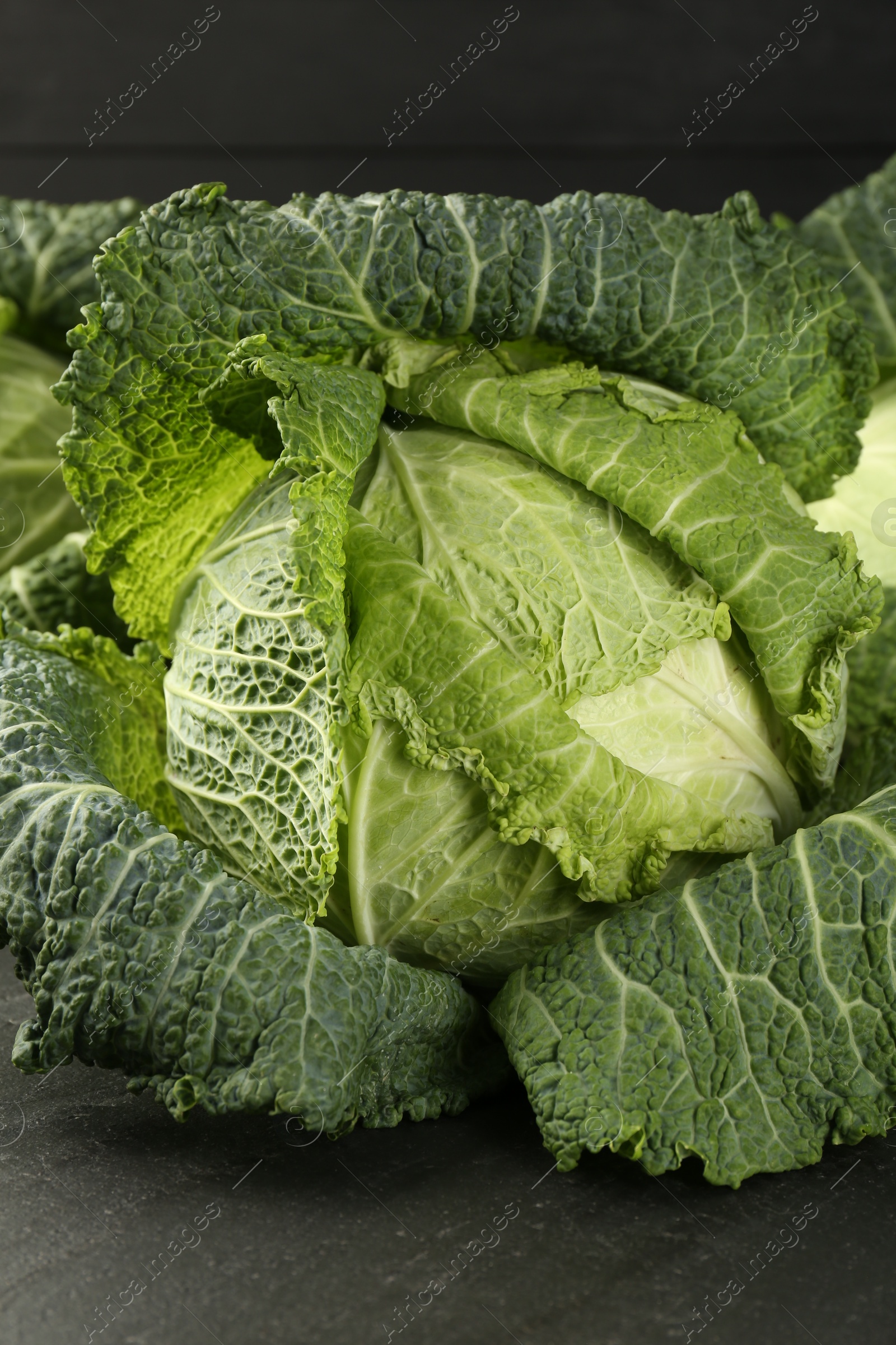 Photo of Fresh Savoy cabbages on dark table, closeup