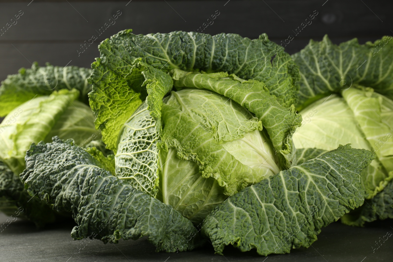 Photo of Fresh Savoy cabbages on dark table, closeup