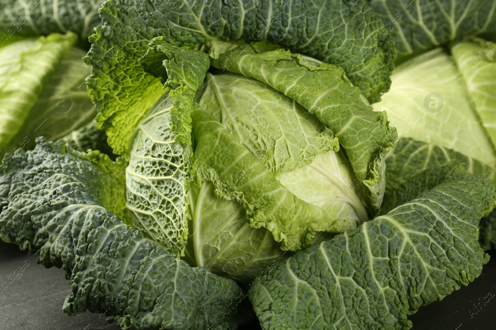 Photo of Fresh Savoy cabbages on dark table, closeup