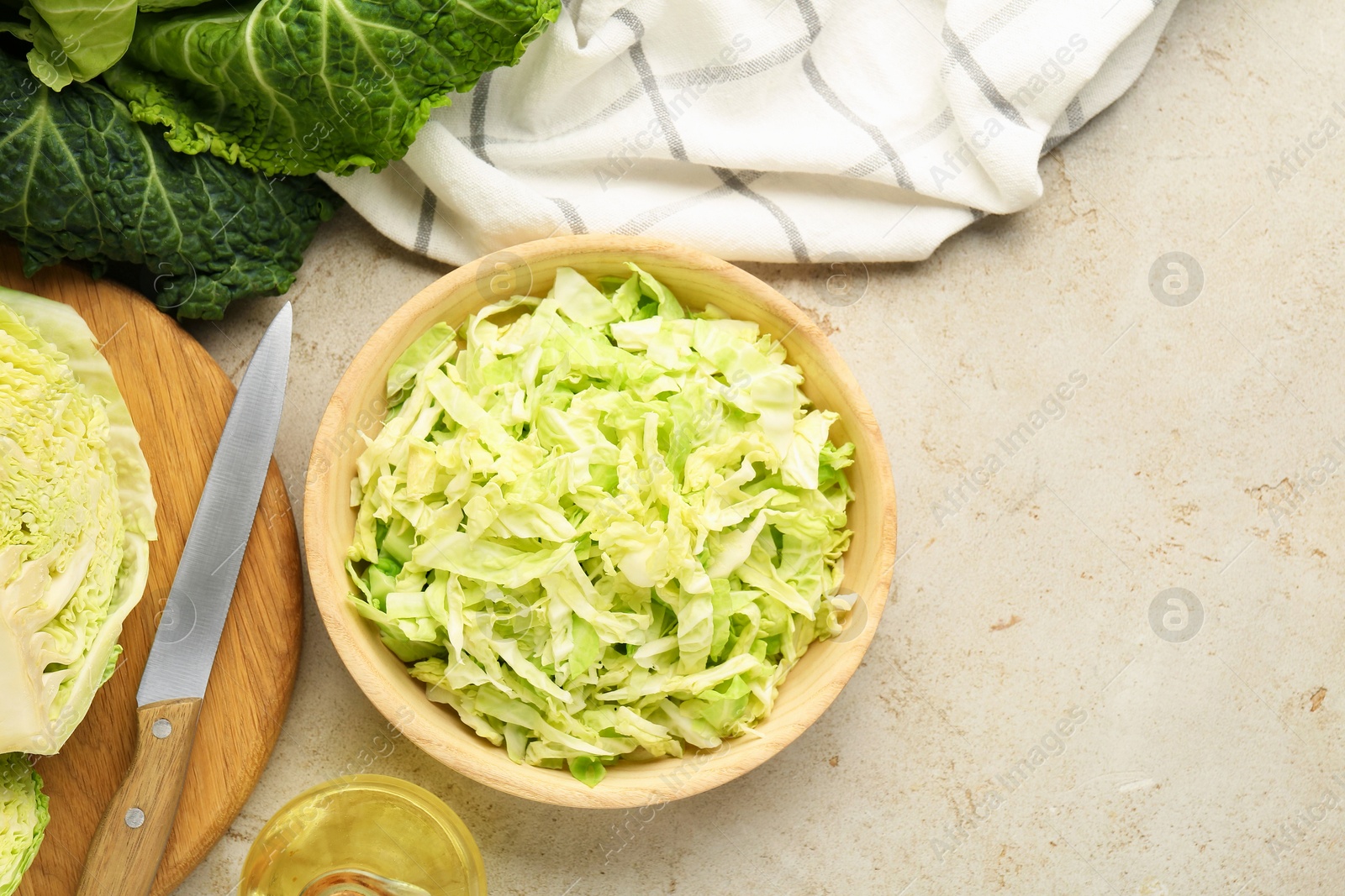 Photo of Cut fresh Savoy cabbage, knife and oil on light table, flat lay. Space for text