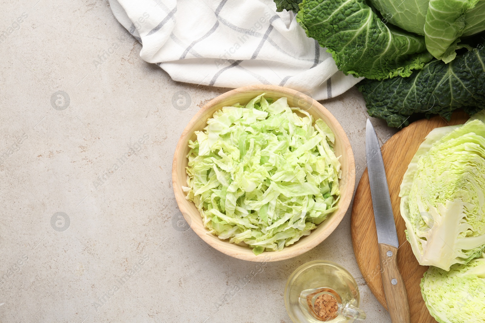 Photo of Cut fresh Savoy cabbage, knife and oil on light table, flat lay. Space for text