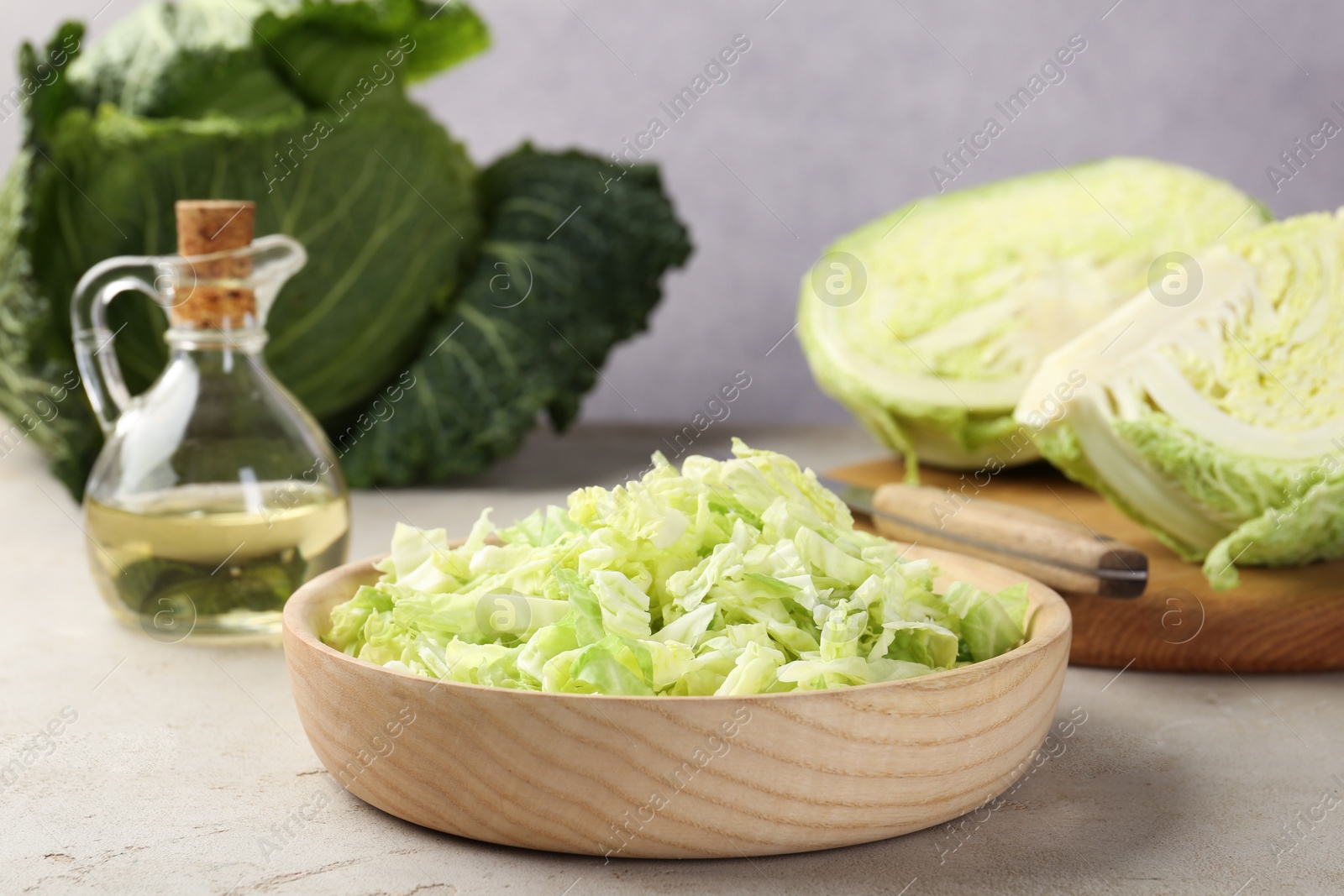 Photo of Fresh Savoy cabbages and oil on light table, closeup